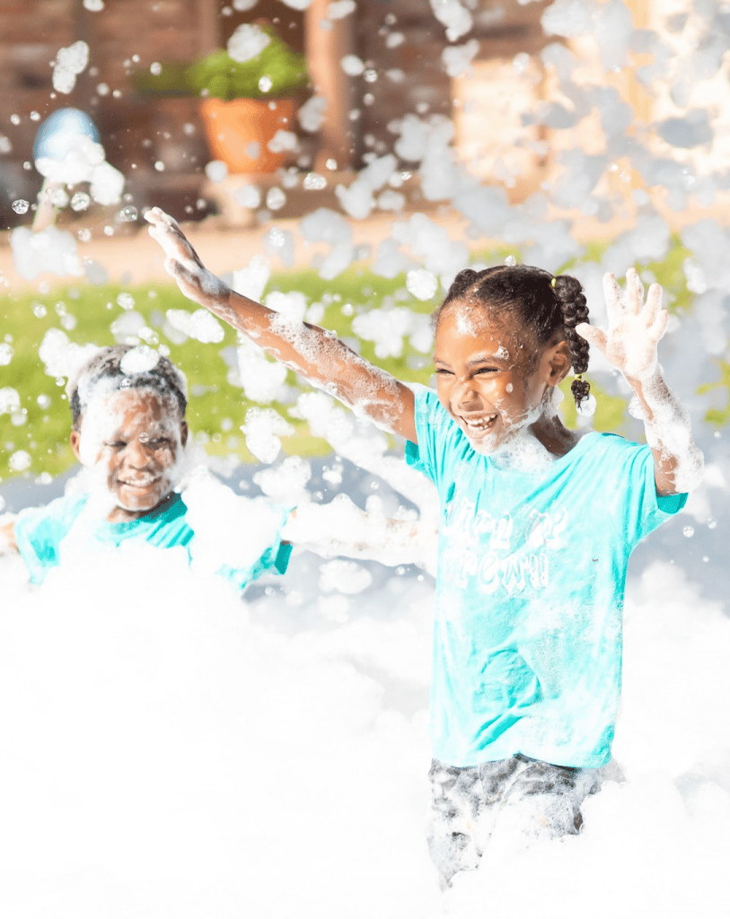 A child surrounded by foam during an outdoor party